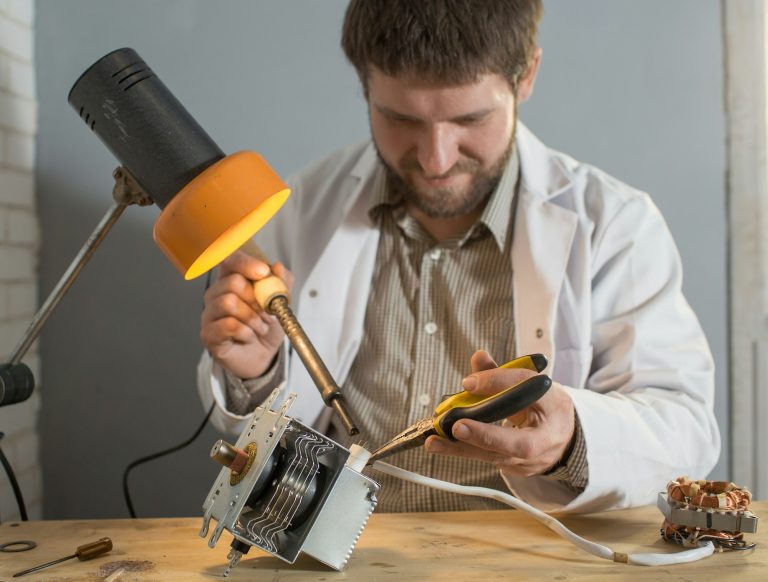 a man soldering iron solders a part from an electrical appliance. the concept of repair of equipment